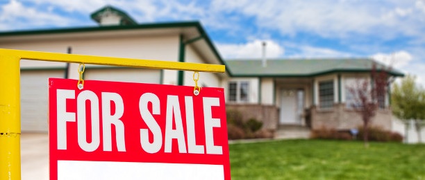 Real Estate Sign in front of a House for Sale with Focus on the Sign